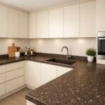 کابینت‌های کرم روشن با صفحه کابینت کورین قهوه‌ای تیره با دانه‌های کرم در آشپزخانه مدرن
